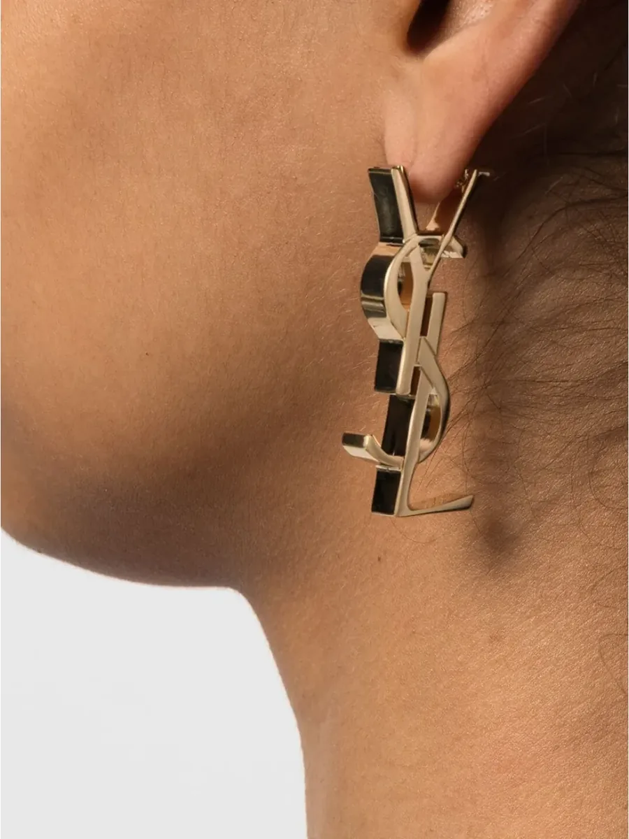 Gold-tone YSL monogram earring worn on the ear, side view