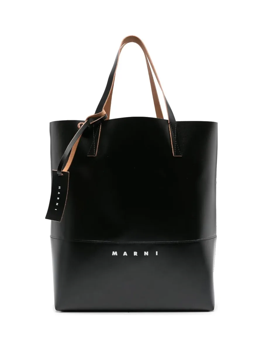 Black faux-leather tote with tan handles, a hanging tag and white logo print, front view