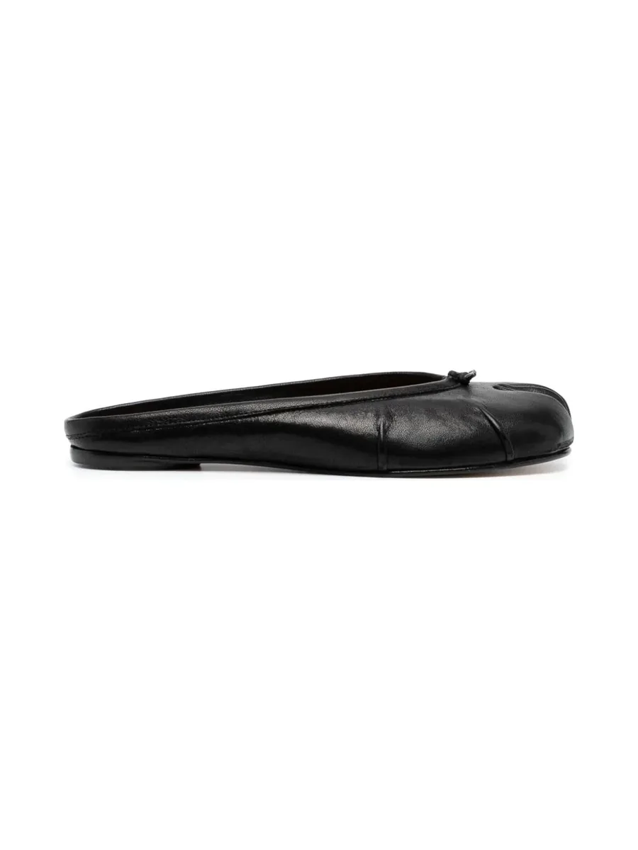 Black leather split-toe mule with a knot at the front and a flat sole, side view